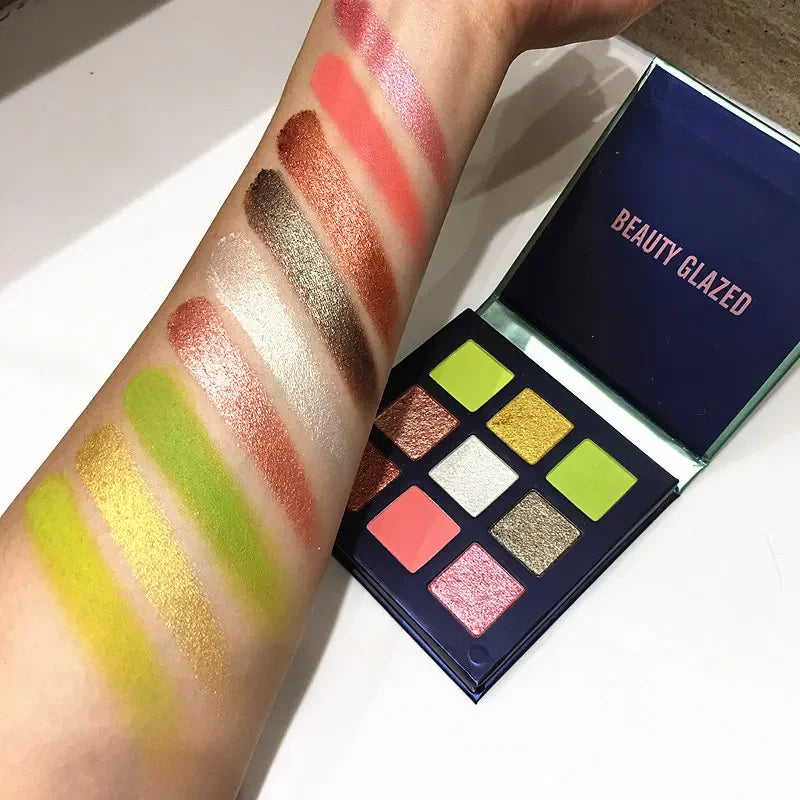 Eyeshadow palette with nine colors, showcasing shimmer and matte shades, swatched on a forearm.