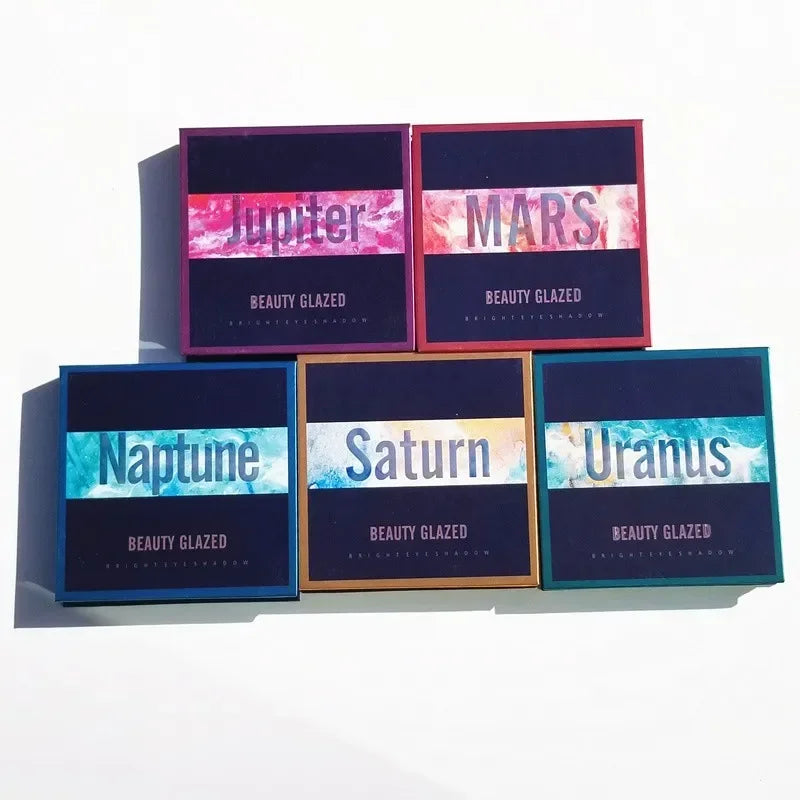 Eyeshadow palette featuring five boxes labeled Jupiter, Mars, Neptune, Saturn, and Uranus with colorful designs.